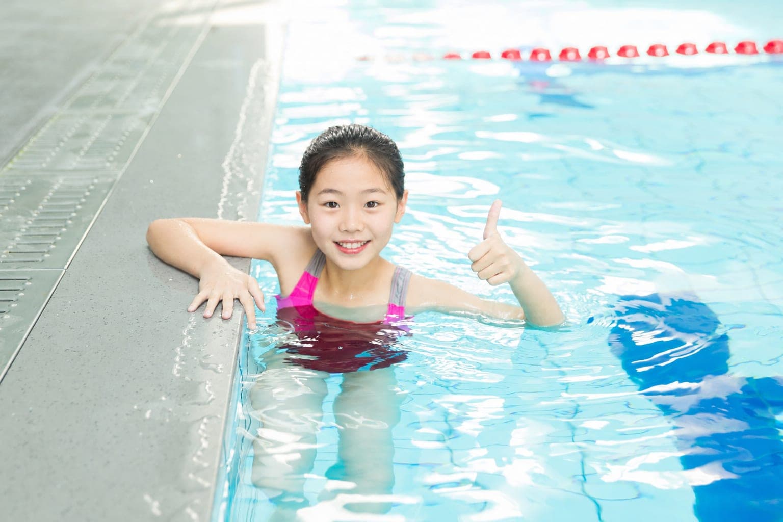 Child giving a thumbs up in the pool after a SwimSafer preparation lesson